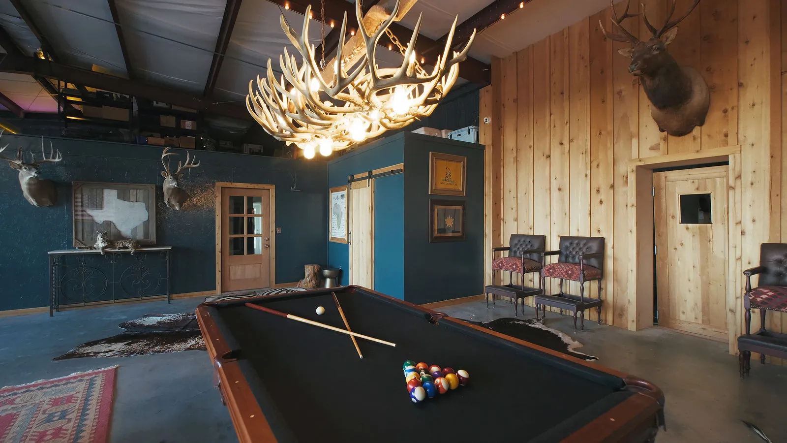 Pool table beneath an antler chandelier
